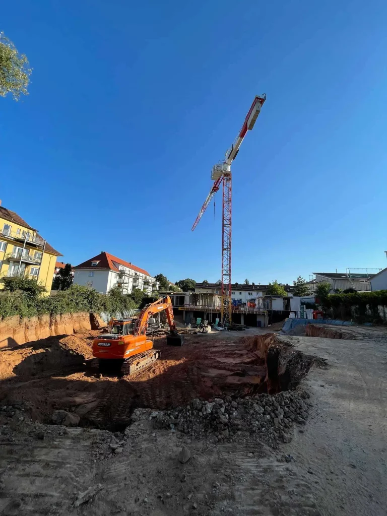 Erdarbeiten: Erdaushub Großprojekt in Annweiler, Bagger und Kran arbeiten zusammen
