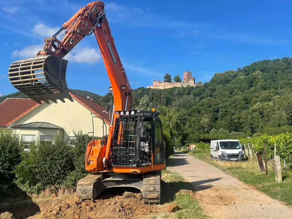 Über uns: Großer Bagger der Wadlinger Gmbh vor der Burg Trifels in Annweiler